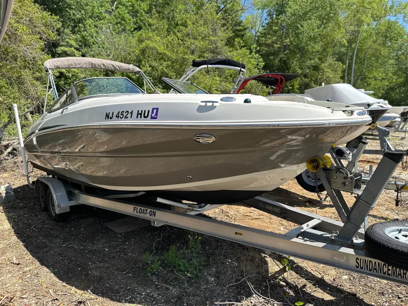 Slide: The Image of 2016 Stingray 234 LR boat on trailer, parked outdoors with trees in the background. - 38
