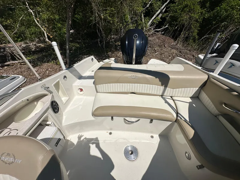 Slide: The Image of 2016 Stingray 234 LR boat interior with beige seating and outboard motor, surrounded by trees. - 48