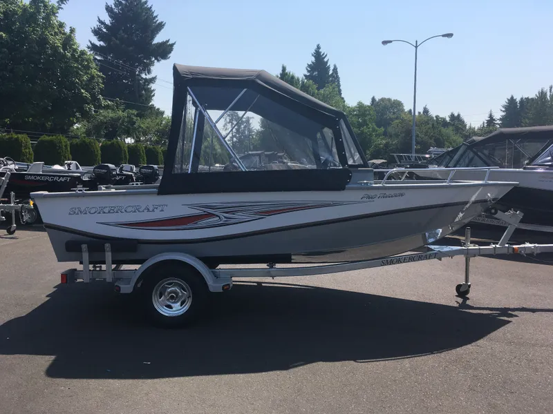Slide: The Image of 2017 Smoker Craft PRO TRACER boat with canopy on trailer in outdoor lot. - 5