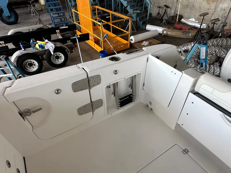 Slide: The Image of 2026 Edgewater 262CX Crossover boat interior with open storage compartments in a workshop setting. - 14