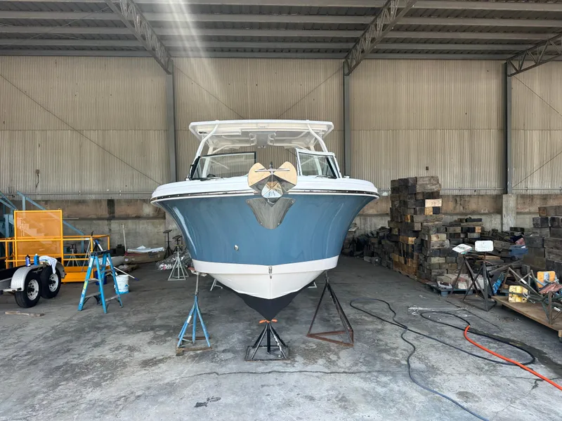 Slide: The Image of 2026 Edgewater 262CX Crossover boat in a warehouse, front view, under maintenance. - 2
