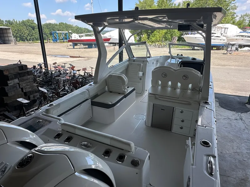 Slide: The Image of 2026 Edgewater 262CX Crossover boat interior with seating and storage, docked in a marina. - 8