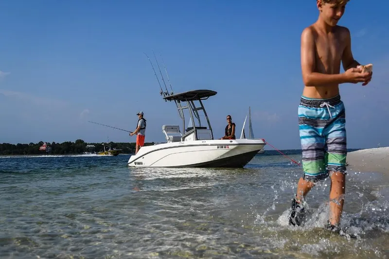 Slide: The Image of 2023 Yamaha Boats 190 FSH Sport in shallow water with people fishing and playing. - 10