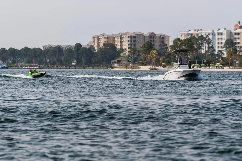Slide: The Image of 2023 Yamaha Boats 190 FSH Sport cruising on a scenic waterfront. - 6