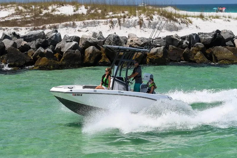 Slide: The Image of 2023 Yamaha Boats 190 FSH Sport cruising in clear waters near rocky shoreline. - 7