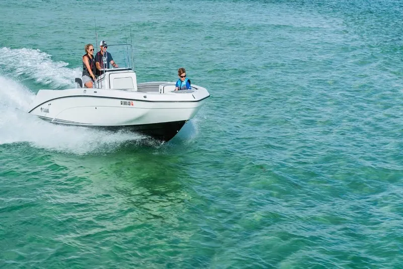 Slide: The Image of 2023 Yamaha Boats 210 FSH cruising on clear blue water. - 4