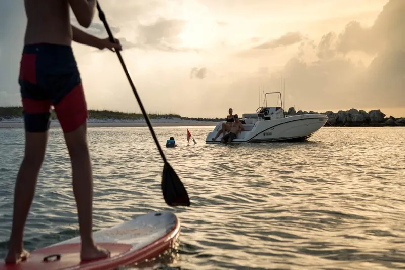 Slide: The Image of Person paddleboarding near a 2023 Yamaha Boats 210 FSH at sunset. - 6