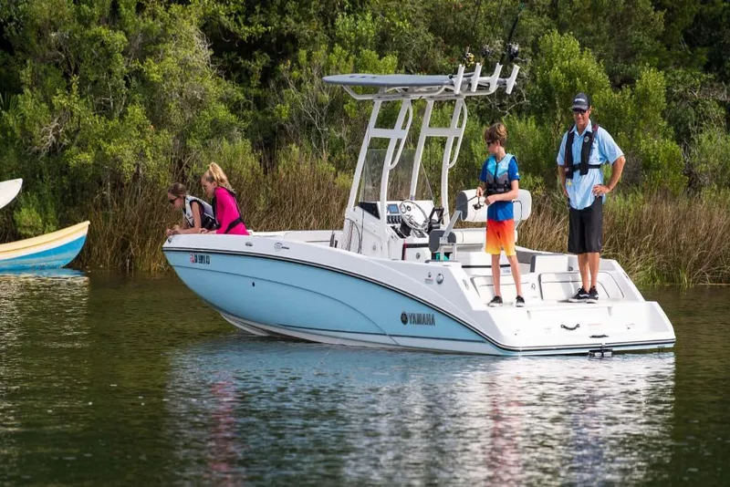 Slide: The Image of 2023 Yamaha Boats 210 FSH Sport on a calm lake with people fishing. - 6