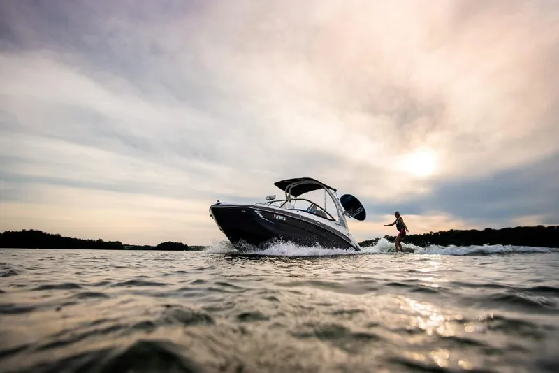 Slide: The Image of 2023 Yamaha Boats 212X on water at sunset with wakeboarder. - 3
