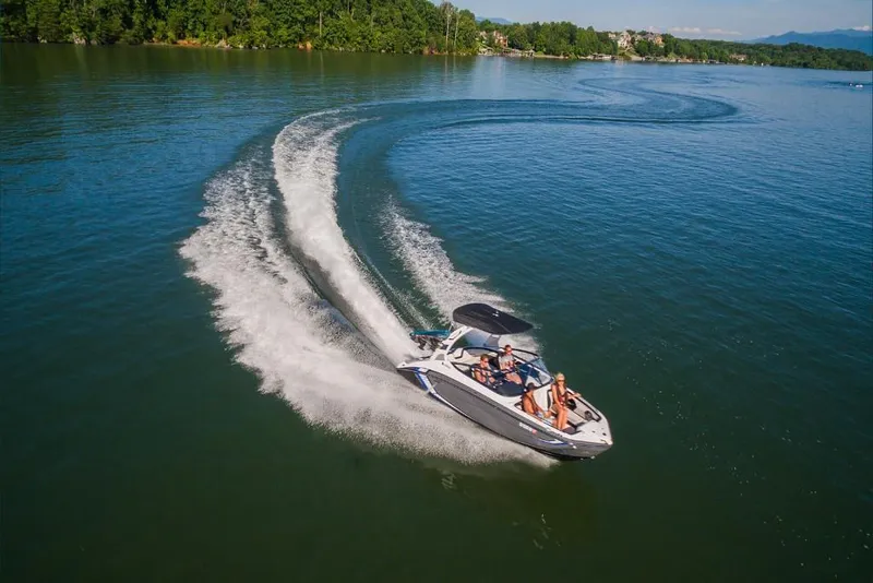 Slide: The Image of 2023 Yamaha Boats 212X speeding on a lake with lush green shoreline. - 6