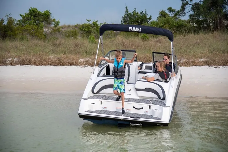 Slide: The Image of 2023 Yamaha Boats SX195 docked on a sandy beach with family onboard. - 4