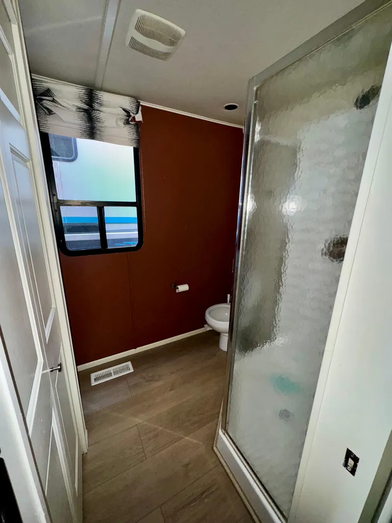 Slide: The Image of 2008 Sumerset Waterways houseboat bathroom with shower, window, and brown walls. - 12