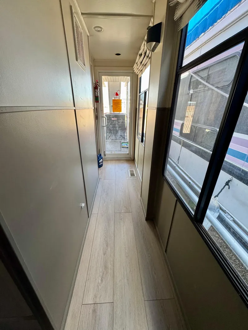 Slide: The Image of Narrow hallway inside 2008 Sumerset Waterways Houseboat, featuring wood flooring and large windows. - 17