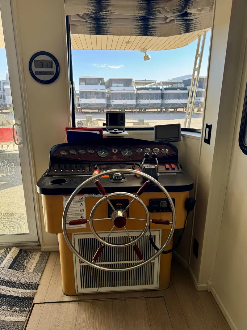 Slide: The Image of 2008 Sumerset Waterways Houseboat helm with steering wheel and control panel, docked at marina. - 2