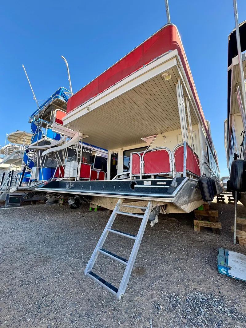 Slide: The Image of 2008 Sumerset Waterways Houseboat with red accents, docked on land, ladder access visible. - 30
