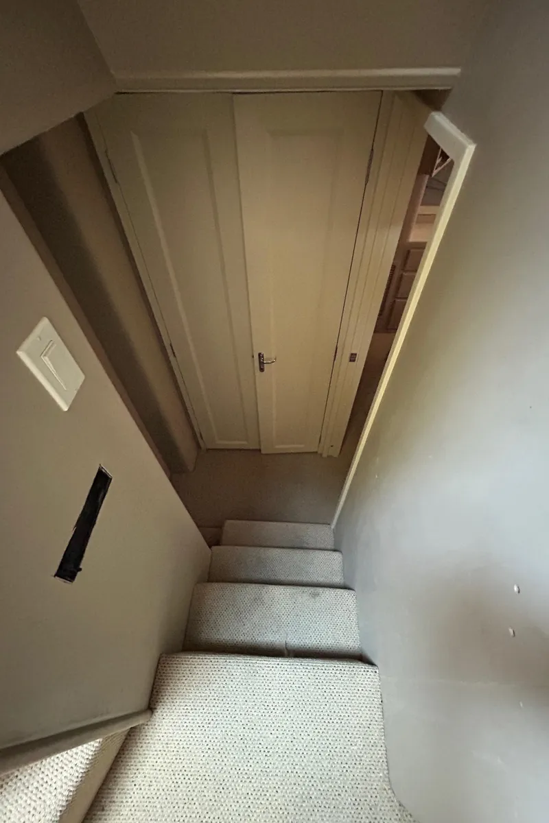 Slide: The Image of Staircase inside 1991 Hatteras Cockpit Motor Yacht, leading to a closed door. - 21