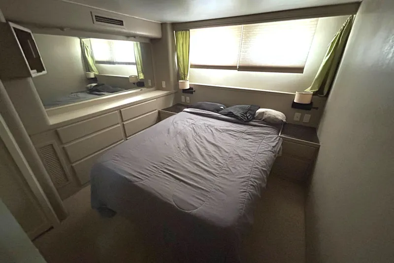 Slide: The Image of 1991 Hatteras Cockpit Motor Yacht bedroom with bed, window, and storage cabinets. - 24