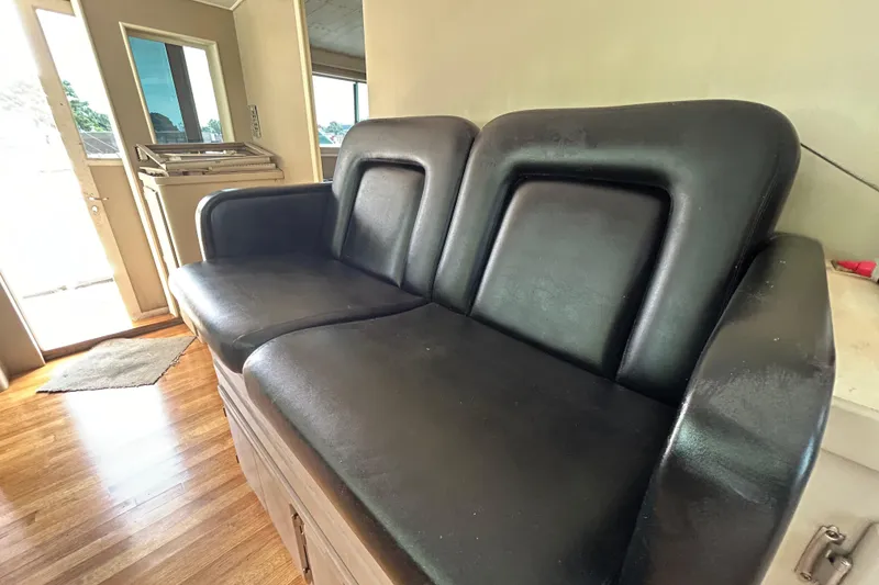 Slide: The Image of 1991 Hatteras Cockpit Motor Yacht interior with black leather seating and wooden flooring. - 31