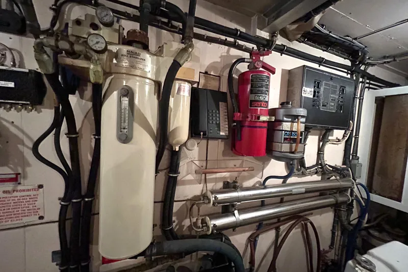 Slide: The Image of Engine room of a 1991 Hatteras Cockpit Motor Yacht with various equipment and piping. - 44