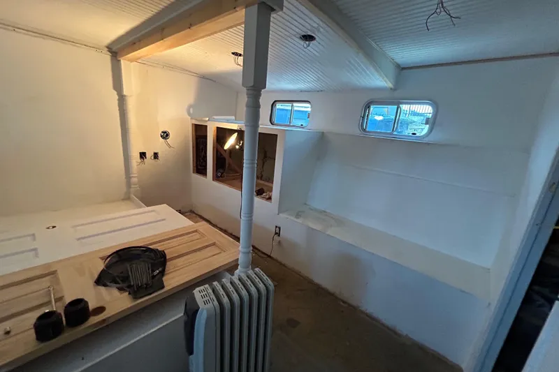 Slide: The Image of 1991 Hatteras Cockpit Motor Yacht interior under renovation, featuring white walls and small windows. - 9