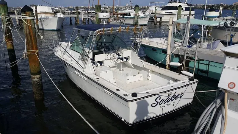 The Image of 1985 Pursuit Tiara 2700 Open boat docked in marina, white exterior, calm water. - 1
