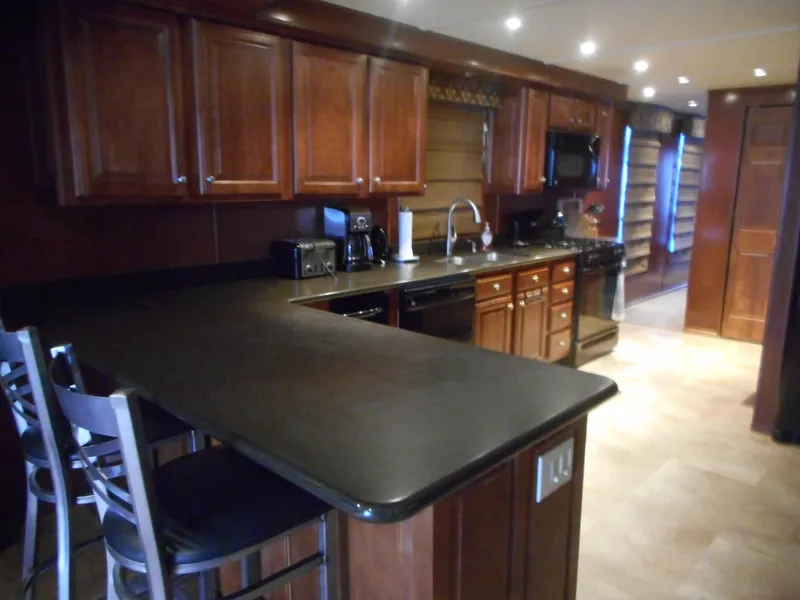 Slide: The Image of Kitchen floor with beige tile pattern, dark cabinets, and appliances. - 11
