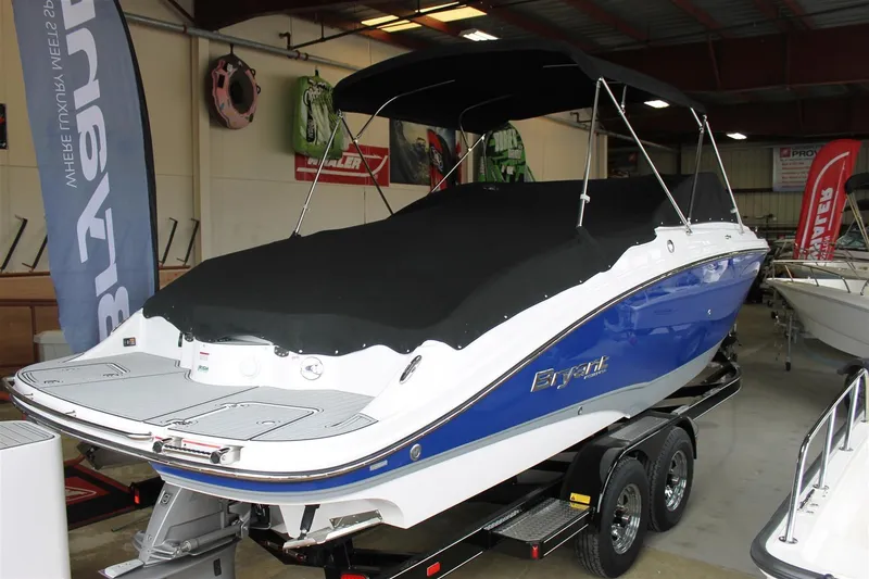 Slide: The Image of 2018 Bryant Potenza boat with blue hull, covered and on trailer in showroom. - 2