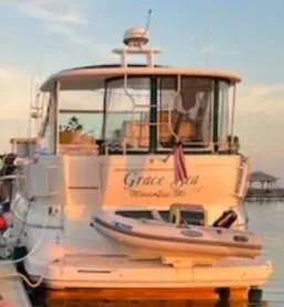 Slide: The Image of 2000 Cruisers Yachts 4450 Express Motor Yacht docked at sunset with dinghy attached. - 4