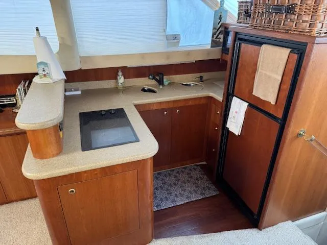Slide: The Image of 2000 Cruisers Yachts 4450 Express Motor Yacht interior kitchen with wood cabinetry and modern appliances. - 41