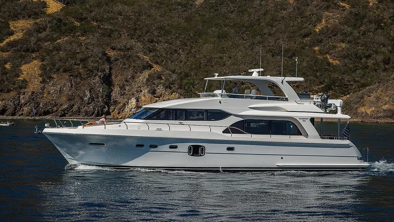 The Image of Luxury 2025 Hampton 650 Pilothouse yacht cruising near rocky coastline. - 0
