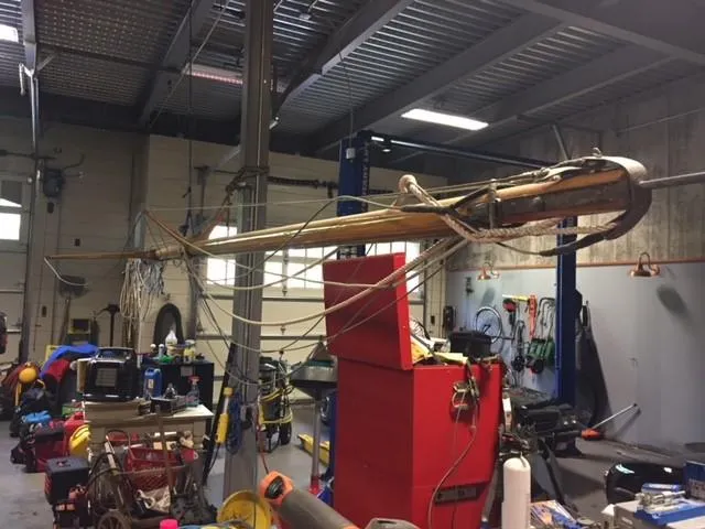 Slide: The Image of Workshop with Herreshoff Watch Hill 15 mast, 1994 model, surrounded by tools and equipment. - 13