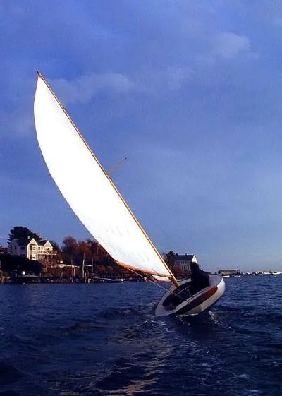 Slide: The Image of Sailboat on water, Herreshoff Watch Hill 15, 1994, with houses in the background. - 5