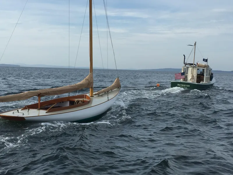 Slide: The Image of Sailboat Herreshoff Watch Hill 15, 1994 model, towed by a motorboat on open water. - 8