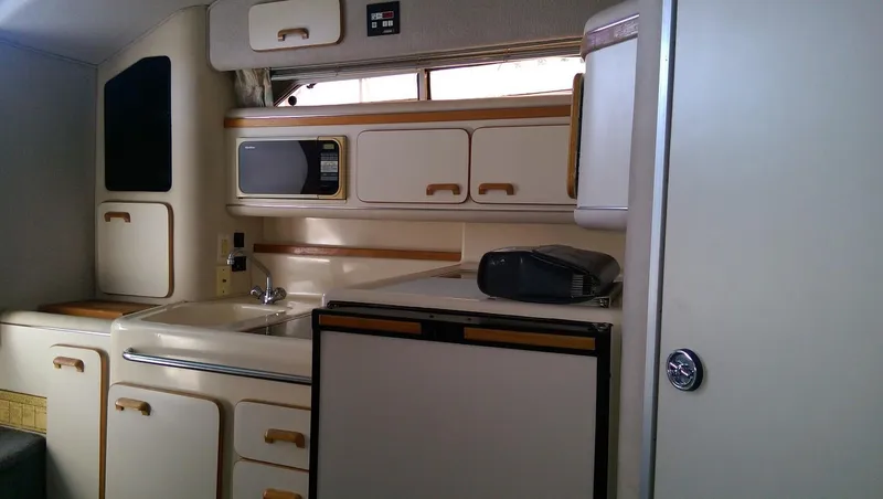Slide: The Image of 1993 Sea Ray 330 Express Cruiser kitchen with sink, microwave, and refrigerator. - 11