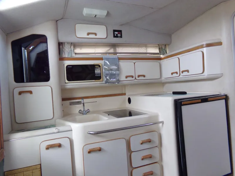 Slide: The Image of 1993 Sea Ray 330 Express Cruiser kitchen with white cabinets and appliances. - 16