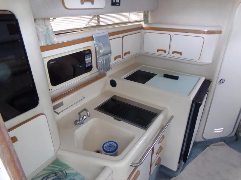 Slide: The Image of 1993 Sea Ray 330 Express Cruiser kitchen with sink, stove, and storage cabinets. - 18