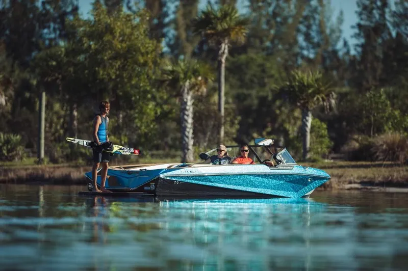 Slide: The Image of 2023 Nautique Ski boat on a lake with people and a water skier. - 0