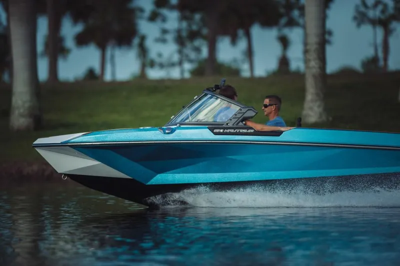 Slide: The Image of 2023 Nautique Ski boat cruising on a lake with two passengers. - 1