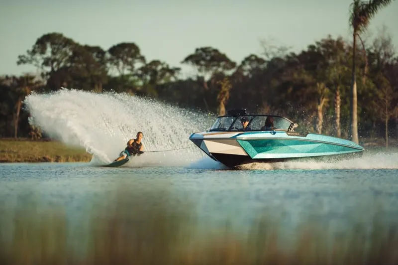 Slide: The Image of 2023 Nautique Ski boat towing a water skier on a lake. - 11