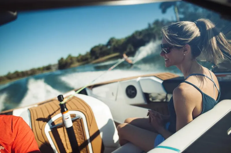 Slide: The Image of 2023 Nautique Ski boat on a lake with passengers and a water skier. - 13