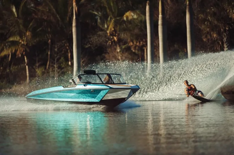 Slide: The Image of 2023 Nautique Ski boat towing a water skier on a calm lake. - 14