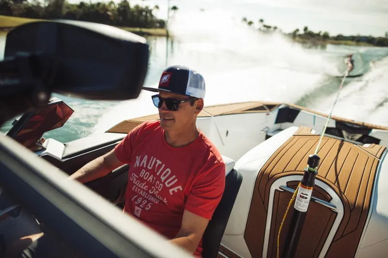 Slide: The Image of Man driving 2023 Nautique Ski boat on a sunny day. - 15