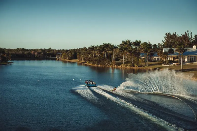 Slide: The Image of 2023 Nautique Ski boat towing a water skier on a serene lake. - 24