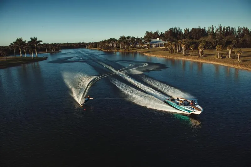 Slide: The Image of 2023 Nautique Ski boat towing a water skier on a scenic lake. - 25