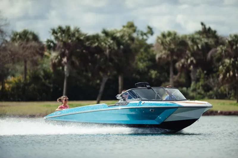 Slide: The Image of 2023 Nautique Ski boat cruising on a lake with palm trees in the background. - 3