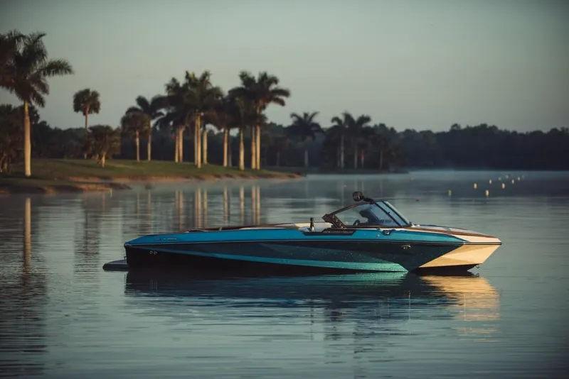 Slide: The Image of 2023 Nautique Ski boat on a calm lake with palm trees in the background. - 30