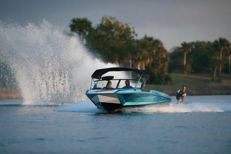 Slide: The Image of 2023 Nautique Ski boat towing a water skier on a lake. - 32
