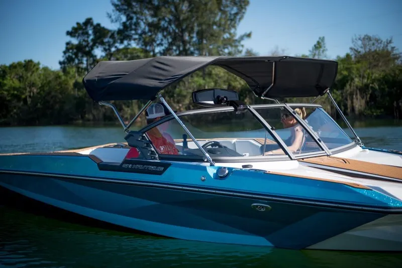 Slide: The Image of 2023 Nautique Ski boat on a serene lake with passengers. - 33