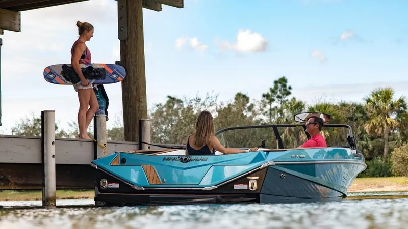 Slide: The Image of 2023 Nautique Ski boat with people wakeboarding at a dock. - 35