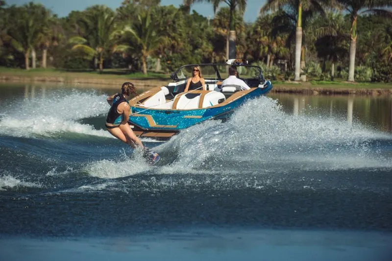 Slide: The Image of 2023 Nautique Ski boat towing a wakeboarder on a sunny lake. - 37